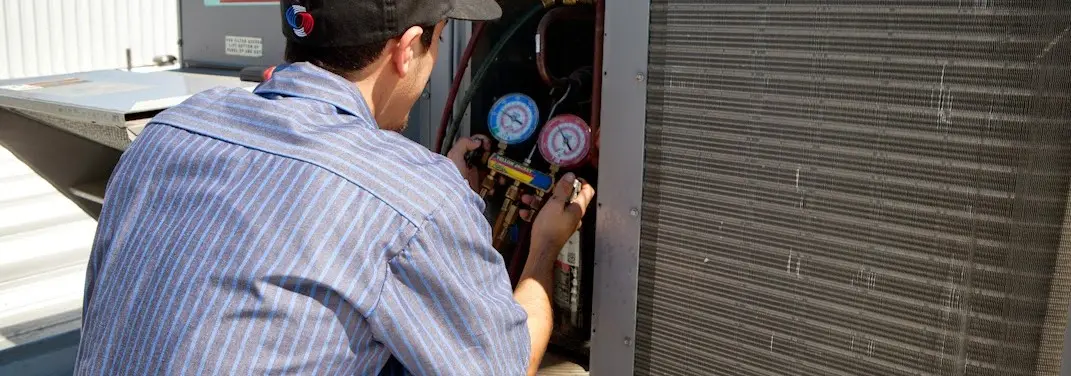 HVAC technician servicing a condenser unit in Lochearn
